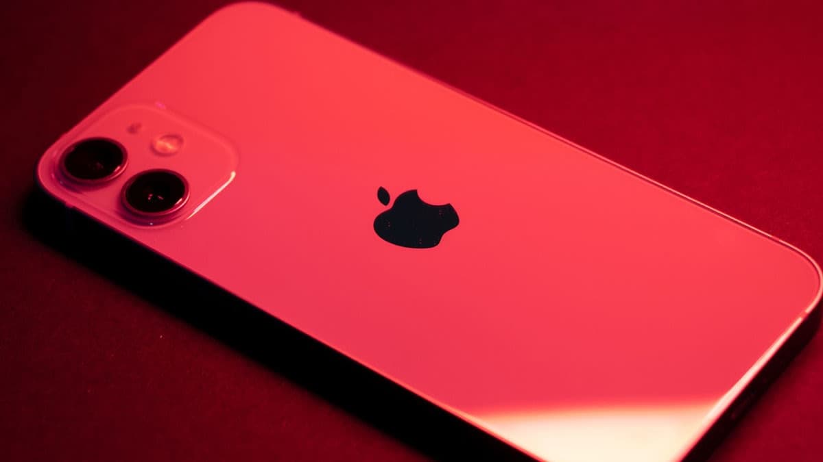Back of an Apple iPhone lit in red, showing the dual camera and Apple logo