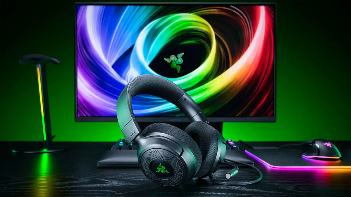 Razer Kraken V4 X Sensa HD Haptics headset on a gaming desk with a Razer monitor, mouse and RGB mat